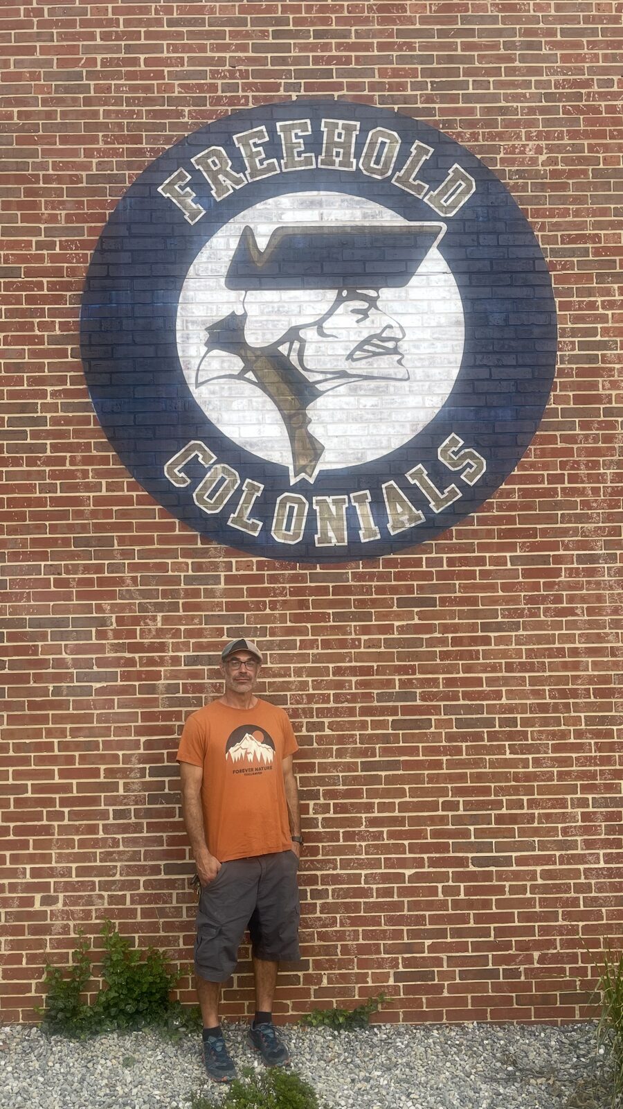 Matthew standing below the completed Freehold Colonials wall print to show its installed scale